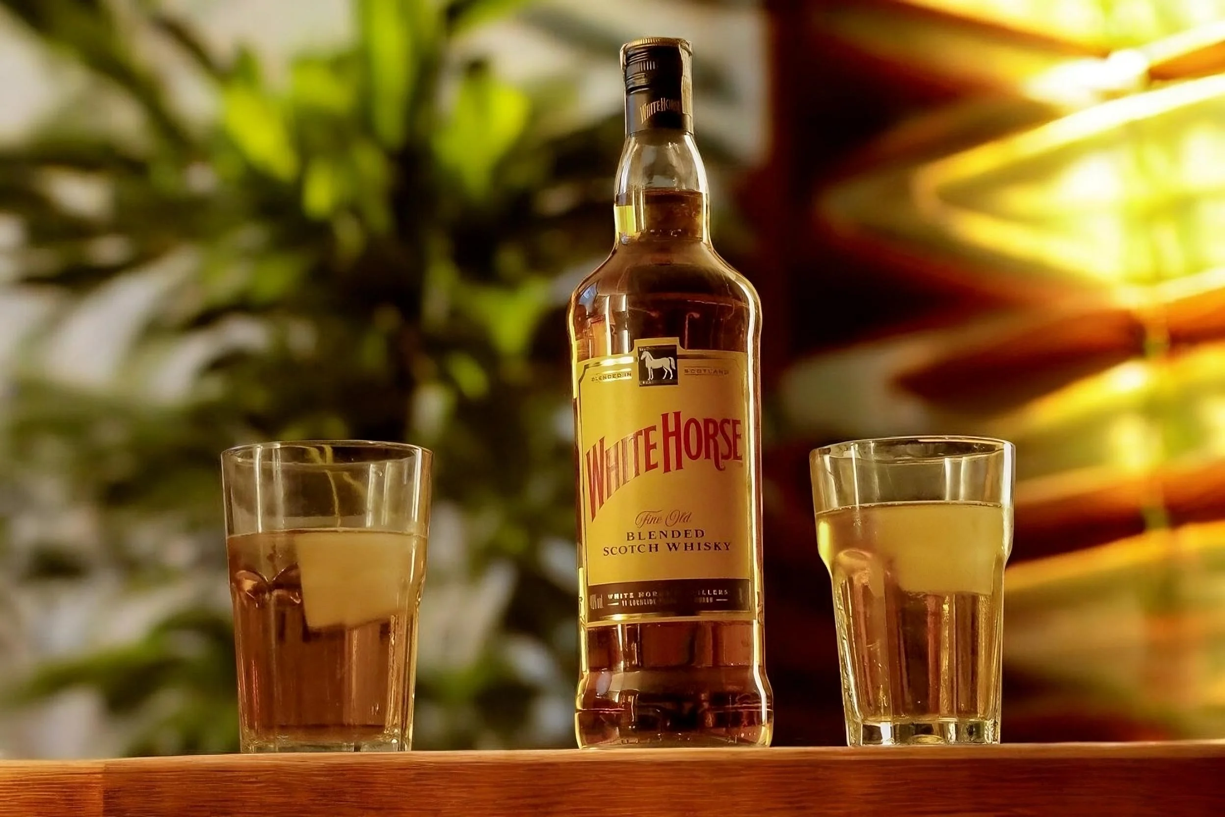 Uma garrafa do Whisky Cavalo Branco com dois copos da bebida ao lado